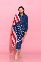 Portrait female athlete wrapped in American Flag against pink background photo