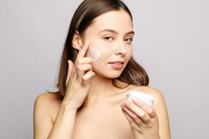 portrait of a laughing woman applying face cream photo