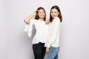 dos riendo muchachas en blanco blanco camisetas mirando dentro el cámara foto