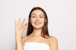 Beautiful Smiling Young Woman Holding Fish Oil Pill In Hand. photo