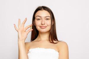 Beautiful Smiling Young Woman Holding Fish Oil Pill In Hand. photo