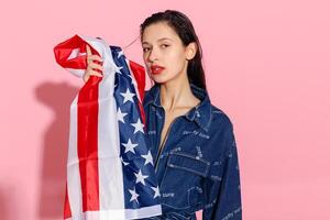 Portrait female athlete wrapped in American Flag against pink background photo