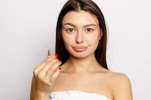 Beautiful Smiling Young Woman Holding Fish Oil Pill In Hand. photo