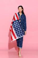 Portrait female athlete wrapped in American Flag against pink background photo