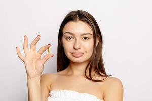 Beautiful Smiling Young Woman Holding Fish Oil Pill In Hand. photo