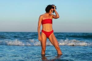 Sexy back of a beautiful woman in red bikini on sea background photo