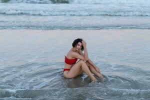 Sexy back of a beautiful woman in red bikini on sea background photo