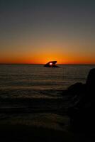 The sunken ship of Cape May New Jersey during sunset. The sun lining up perfectly with hull to look like a glowing eye. The sky has beautiful colors of orange almost like it is on fire. photo