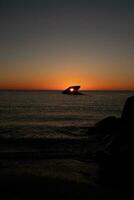 The sunken ship of Cape May New Jersey during sunset. The sun lining up perfectly with hull to look like a glowing eye. The sky has beautiful colors of orange almost like it is on fire. photo