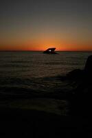 This is the beautiful image of the sunken ship of Cape May New Jersey during sunset. The sky has beautiful colors of orange almost like it is on fire. The fiery shades reflecting off the water. photo