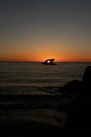 The sunken ship of Cape May New Jersey during sunset. The sun lining up perfectly with hull to look like a glowing eye. The sky has beautiful colors of orange almost like it is on fire. photo