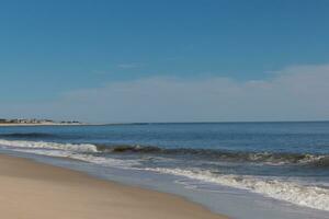 Beautiful image of the Cape May beach. Pretty blue colors all around. The ocean looking so serene with a bit of clouds in the sky. photo