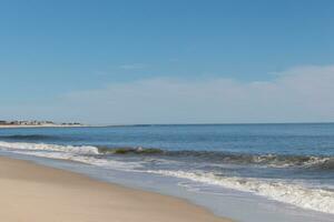 Beautiful image of the Cape May beach. Pretty blue colors all around. The ocean looking so serene with a bit of clouds in the sky. photo