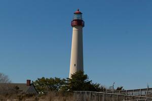 This is Cape May point lighthouse seen from the beach. The tall white structure with red metal serves as a beacon of safety. photo
