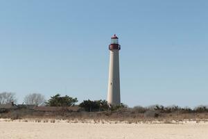 esta es capa mayo punto faro visto desde el playa. el alto blanco estructura con rojo metal sirve como un Faro de seguridad. foto