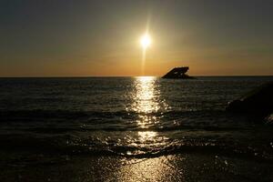 Sunset beach in Cape May New Jersey where you can get a great view of the sun going down across the ocean and the bay. The reflection of the sun on the water with the sunken ship looks so beautiful. photo