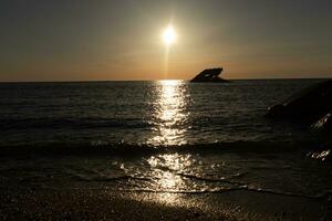 Sunset beach in Cape May New Jersey where you can get a great view of the sun going down across the ocean and the bay. The reflection of the sun on the water with the sunken ship looks so beautiful. photo