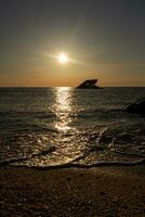 Sunset beach in Cape May New Jersey where you can get a great view of the sun going down across the ocean and the bay. The reflection of the sun on the water with the sunken ship looks so beautiful. photo