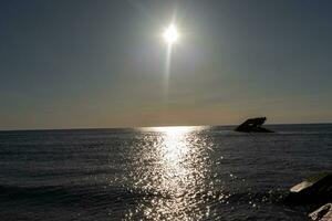 Sunset beach in Cape May New Jersey where you can get a great view of the sun going down across the ocean and the bay. The reflection of the sun on the water with the sunken ship looks so beautiful. photo