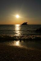 Sunset beach in Cape May New Jersey where you can get a great view of the sun going down across the ocean and the bay. The reflection of the sun on the water with the sunken ship looks so beautiful. photo