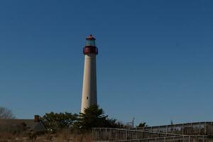 This is Cape May point lighthouse seen from the beach. The tall white structure with red metal serves as a beacon of safety. photo