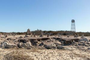 This rocky beach was at Sunset Beach in Cape May New Jersey. This beach is iconic for all the pebbles and rocks that are on it. The sand dunes in the back really add to this image. photo