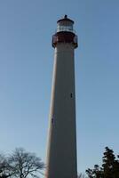 This is Cape May point lighthouse in New Jersey. I love the white look of its tower and the red top to it that stands out from so many. This beacon of hope helps people at sea to navigate. photo