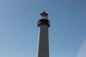 This is Cape May point lighthouse in New Jersey. I love the white look of its tower and the red top to it that stands out from so many. This beacon of hope helps people at sea to navigate. photo