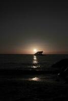 Sunset beach in Cape May New Jersey where you can get a great view of the sun going down across the ocean and the bay. The reflection of the sun on the water with the sunken ship looks so beautiful. photo