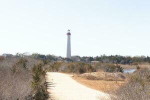 This pale white path leads to a beacon of hope. The Cape May point lighthouse stands tall in the distance. photo