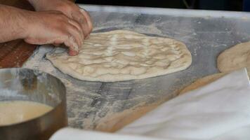 the chef's hands form a round pizza base from the dough with his hands. video