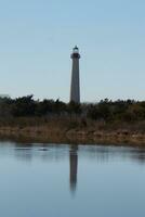 Cape May Point Lighthouse casting a beautiful reflection in the still pond. Brown foliage all around showing the Fall season. photo