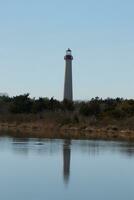 Cape May Point Lighthouse casting a beautiful reflection in the still pond. Brown foliage all around showing the Fall season. photo