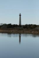 Cape May Point Lighthouse casting a beautiful reflection in the still pond. Brown foliage all around showing the Fall season. photo