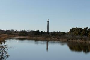 Cape May Point Lighthouse casting a beautiful reflection in the still pond. Brown foliage all around showing the Fall season. photo