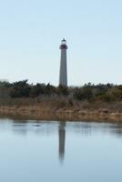 Cape May Point Lighthouse casting a beautiful reflection in the still pond. Brown foliage all around showing the Fall season. photo