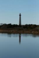 Cape May Point Lighthouse casting a beautiful reflection in the still pond. Brown foliage all around showing the Fall season. photo