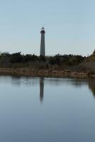 Cape May Point Lighthouse casting a beautiful reflection in the still pond. Brown foliage all around showing the Fall season. photo