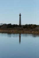 Cape May Point Lighthouse casting a beautiful reflection in the still pond. Brown foliage all around showing the Fall season. photo