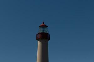 This is the top image of Capy May point lighthouse. The red metal top stands out against the white brick of the tower. photo