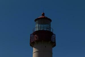 This is the top image of Capy May point lighthouse. The red metal top stands out against the white brick of the tower. photo