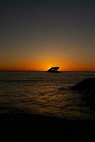 Sunset beach in Cape May New Jersey where you can get a great view of the sun going down across the ocean and the bay. The reflection of the sun on the water with the sunken ship looks so beautiful. photo