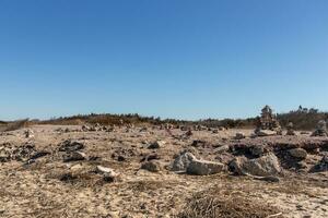 This rocky beach was at Sunset Beach in Cape May New Jersey. This beach is iconic for all the pebbles and rocks that are on it. The sand dunes in the back really add to this image. photo