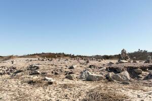 This rocky beach was at Sunset Beach in Cape May New Jersey. This beach is iconic for all the pebbles and rocks that are on it. The sand dunes in the back really add to this image. photo