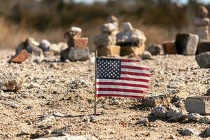 esta hermosa americano bandera estaba en esta arena Monumento ese estaba creado en el playa. yo amado el Mira de esta soplo en el viento con todas el piedras apilado arriba alrededor él. pareció muy patriótico. foto