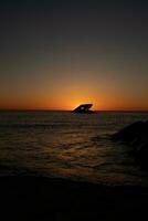 Sunset beach in Cape May New Jersey where you can get a great view of the sun going down across the ocean and the bay. The reflection of the sun on the water with the sunken ship looks so beautiful. photo