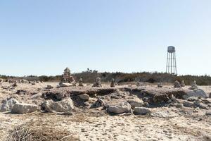 This rocky beach was at Sunset Beach in Cape May New Jersey. This beach is iconic for all the pebbles and rocks that are on it. The sand dunes in the back really add to this image. photo