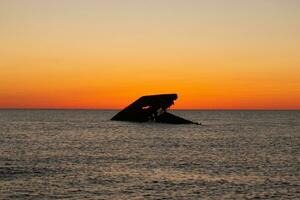 puesta de sol playa en capa mayo nuevo jersey dónde usted lata obtener un genial ver de el Dom yendo abajo a través de el Oceano y el bahía. el reflexión de el Dom en el agua con el hundido Embarcacion mira entonces hermosa. foto