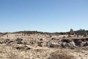 This rocky beach was at Sunset Beach in Cape May New Jersey. This beach is iconic for all the pebbles and rocks that are on it. The sand dunes in the back really add to this image. photo