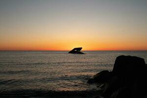 Sunset beach in Cape May New Jersey where you can get a great view of the sun going down across the ocean and the bay. The reflection of the sun on the water with the sunken ship looks so beautiful. photo